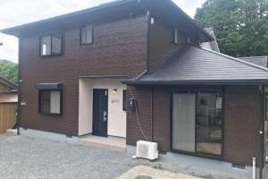 una casa de ladrillo marrón con puerta negra en Guest House Kiyohime, en Tanabe