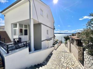 a white house with a pathway next to the water at Apartments Mare in Dramalj
