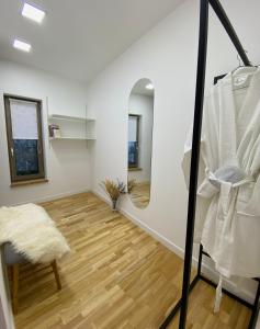 una camera con pareti bianche, specchio e pavimento in legno di Nook. The Design Apartment a Târgu-Mureş