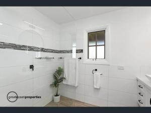 een witte badkamer met een douche en een potplant bij Serenity by the Sea Cottage in Apollo Bay with Jacuzzi in Marengo