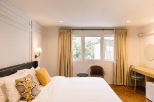 a bedroom with a bed and a desk and a window at The Mellow Pillow Hotel @ Chiang Mai Gate in Chiang Mai