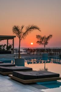 ein Resortpool mit Sonnenuntergang im Hintergrund in der Unterkunft AKASHA Beach Hotel & Spa in Hersonissos