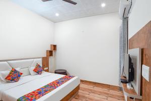 a bedroom with a bed and a flat screen tv at FabHotel Sirtaj Suits in Agra