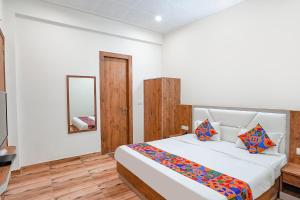a bedroom with a large bed and a mirror at FabHotel Sirtaj Suits in Agra