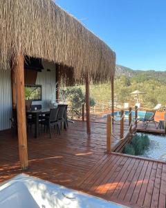 una terraza de madera con mesa de comedor y techo de paja en Lovin Göcek Tiny House Butterfly en Gökçeovacık