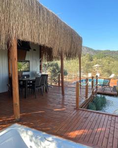 a wooden deck with a dining table and a straw roof at Lovin Göcek Tiny House Butterfly in Gökçeovacık