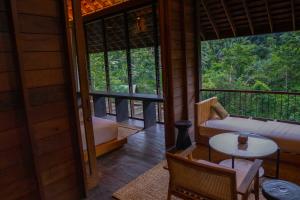 Zimmer mit Sofa, Tisch und Fenster in der Unterkunft Hideaway Village Bali Ubud by Kanaan Hospitality in Ubud