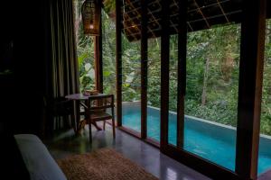 Zimmer mit einem Tisch und Poolblick in der Unterkunft Hideaway Village Bali Ubud by Kanaan Hospitality in Ubud
