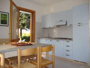a kitchen with white cabinets and a table and chairs at Appartanenti Arcadia in Caorle