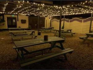 un grupo de mesas de picnic con luces. en The Coach House at The Bull Inn en Milton Keynes