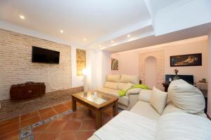 a living room with white furniture and a brick wall at Realejo Príncipe in Granada