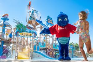 Una ragazza e una mascotte in piedi di fronte a un parco acquatico di Lopesan Costa Bávaro Resort, Spa & Casino a Punta Cana