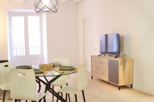 een eetkamer met een tafel met stoelen en een tv bij Mediterranean Way - Cavaller Suites in Tarragona