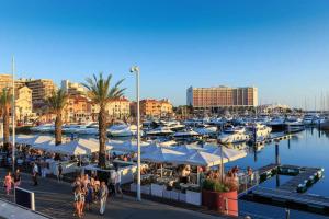 un puerto deportivo con barcos tripulados y gente caminando por ahí en Aquamar 416 by Vilamoura Sun espaçoso, en Vilamoura