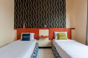 deux lits côte à côte dans une pièce dans l'établissement Urbanview Hotel Syariah Residence Medan by RedDoorz, à Medan
