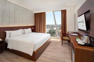 a hotel room with a bed and a large window at Golden Tulip Pontianak in Pontianak