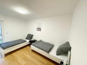 2 Betten in einem Zimmer mit weißen Wänden und Holzböden in der Unterkunft Apartments in Rosbach vor der Höhe in Rosbach vor der Höhe