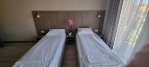 two beds in a room with a vase of flowers at Pensiunea Normandia in Timişoara