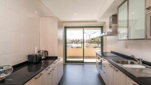 a kitchen with a sink and a large window at Marina Vilamoura Aquamar 120 By Vilamoura Sun in Vilamoura