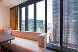 a room with a couch in front of a large window at karaksa hotel colors Tokyo Yaesu in Tokyo