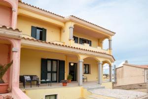 uma casa amarela com uma varanda com um pátio em Casa a Telti by Wonderful Italy em Telti