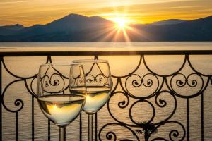 two glasses of white wine on a balcony with the sunset at Residence Casa e Vela in Oggebbio