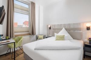 a hotel room with a bed and a desk and a window at Parkhotel Wangerooge in Wangerooge