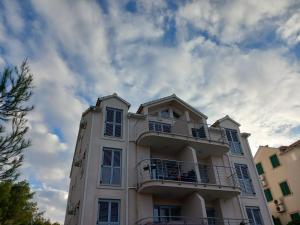 a white building with a balcony and a cloudy sky at 25 King's Landing in Supetar in Supetar
