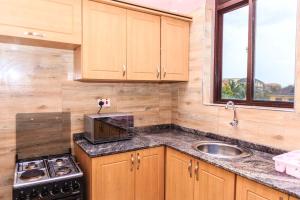 een keuken met houten kasten, een wastafel en een magnetron bij SkyGrey suites in Kampala