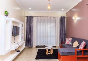 een woonkamer met een blauwe bank en een tv bij SkyGrey suites in Kampala