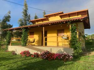 a yellow house with flowers in front of it at Chalés Samambaia in Bananeiras