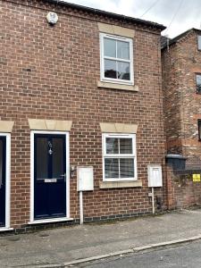 un edificio de ladrillo con una puerta azul y dos ventanas en Newbourne Terrace en Derby