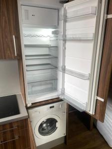 an open refrigerator with a washing machine in it at Cosy studio flat in Muswell Hill in London