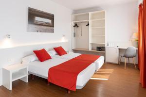 a bedroom with a large white bed with red pillows at Intelier Orange in Benicàssim