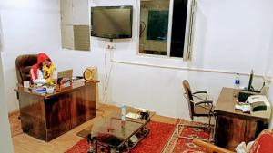 uma sala de estar com uma mesa e uma televisão em The HappyTel em Mussoorie