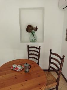 una mesa de madera con 2 sillas y un jarrón con flores en Flat - Casale Angela en Bolsena