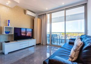 een woonkamer met een blauwe bank en een flatscreen-tv bij Marina View Apartment By VilamouraSun in Vilamoura