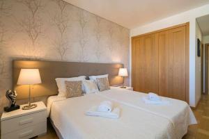 a bedroom with a large white bed with towels on it at Marina Vilamoura - Aquamar 401- Modern Apartment in Vilamoura +41 photos