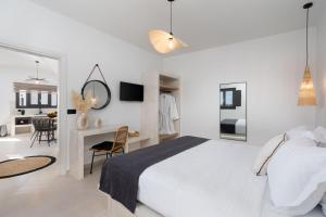 a white bedroom with a large bed and a desk at Almira Luxury Suites in Perivolos