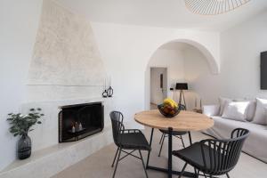 a living room with a table and chairs and a fireplace at Almira Luxury Suites in Perivolos