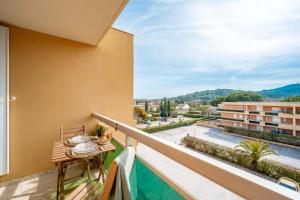 a balcony with a table and a view of a building at Cabana & Le Mimosa Ensoleillé - Plage, Box, Terrasse in Bormes-les-Mimosas