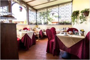 a restaurant with tables with red chairs and windows at B&B Degli Amici in Ciampino
