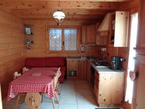 a kitchen with a table and a red couch in a cabin at Appartement "HERISSON" indépendant à Lélex, Monts Jura in Lélex