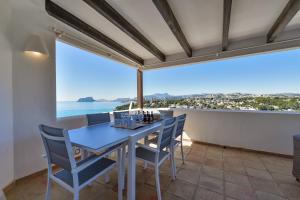 a dining room with a table and chairs and a view of the ocean at BAHÍA DE EL PORTET - By Almarina Villas in Moraira