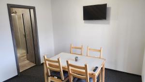a dining room table with three chairs and a television at Penzion-Dubno in Dubno