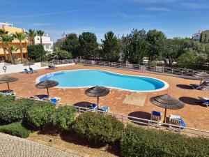 una gran piscina con sombrillas, sillas y orianos en Apartamento Royal Garden T2 by YHA en Conceição