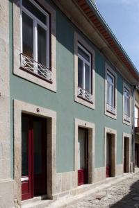 a blue and green building with windows on a street at Guest house Eça Agora! in Vila do Conde