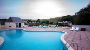 a swimming pool with chairs and tables and a patio at Newquay Bay Resort 181 in Newquay Bay Resort