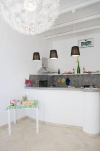 a white kitchen with a table and two pendant lights at B&B La Palma in Santa Marina Salina