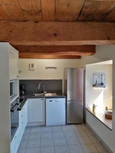 a kitchen with white cabinets and a stainless steel refrigerator at Les Gîtes du Clos in La Tour-dʼAuvergne